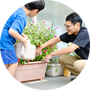 スタッフが子供と植物に水をあげているシーン